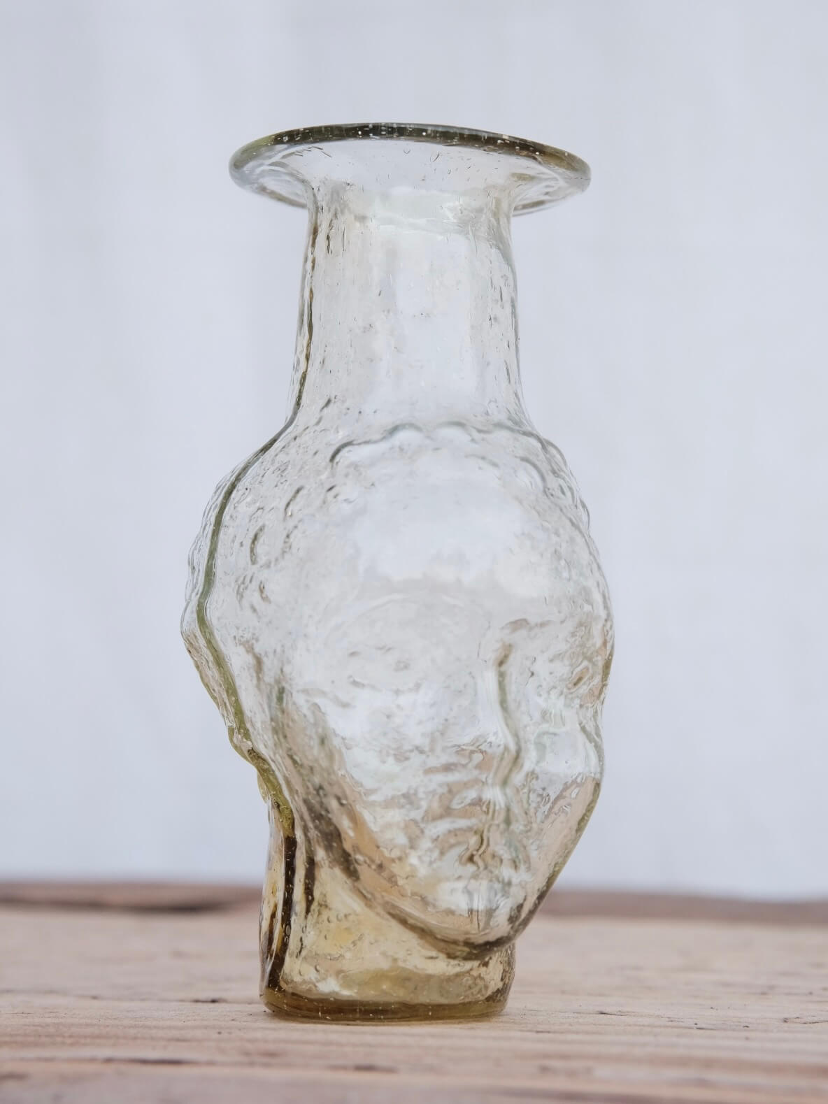Small clear glass vase in the shape of a head. Use it as a vase, candleholder or creamer. Handblown in Paris by La Soufflerie.