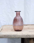 Small raspberry coloured vase sitting on a vintage wooden table. Handblown in Paris by La Soufflerie.